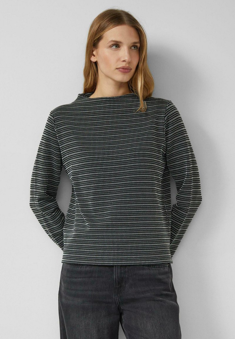 Czarnobiały wzorzysty top z długim rękawem i wysokim kołnierzem. Posiada fakturowany wzór małych kropek na gładkiej tkaninie.