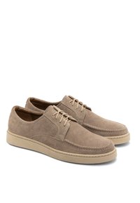 Beżowe zamszowe buty o gładkiej teksturze, okrągłym nosku i minimalnym przeszyciu. Posiadają jasnobeżową gumową podeszwę oraz klasyczny sznurowany fason.
