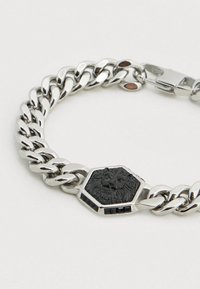 Ασημένιο βραχιόλι με αλυσίδα που διαθέτει εξαγωνικό μαύρο μενταγιόν με λιοντάρι και περίπλοκες λεπτομέρειες, με μαύρες πέτρες ως διακοσμητικά στοιχεία. Κλείσιμο με ασφαλή αγκράφα.