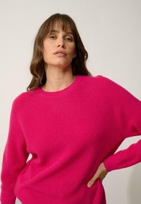 Fuchsia gebreide trui met een ronde hals, raglanmouwen en ribbelstructuur, voorzien van lange mouwen en een relaxte pasvorm.