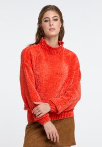 Pulover roșu texturat cu guler înalt, croială lejeră și margini ribificate, asociat cu o fustă din suede maro.