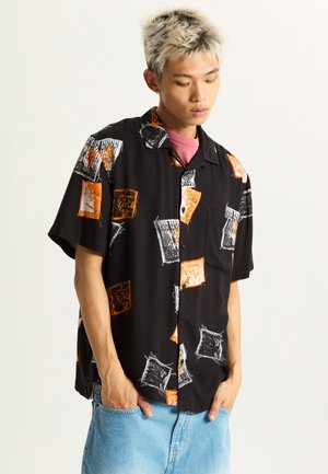 Short-sleeve black shirt featuring orange and white abstract patterns, a relaxed fit, and a single chest pocket.