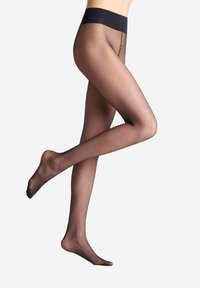 Collant neri trasparenti con una ampia vita opaca e piccoli motivi a pois. Texture liscia, che mette in evidenza le gambe in una posa laterale.