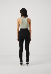 Un débardeur côtelé vert menthe associé à un legging noir taille haute, porté avec des baskets à motifs au design ludique.