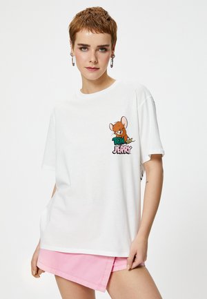 T-shirt en coton blanc avec un design de souris cartoon et le texte "TOM et JERRY" en lettres colorées sur le devant. Manches courtes, coupe décontractée.