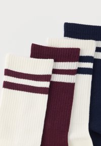 Fire par ribstrikkede sokker foldet, der viser manchetter med vandrette striber i hvid, bordeaux og marineblå farver på en hvid baggrund.