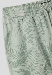 Pantaloni jogger verde chiaro con motivo di foglie di palma, realizzati in tessuto morbido con vita elasticizzata e tasche laterali.