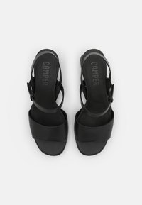Black leather sandals with a wide front strap and adjustable ankle strap. Textured insole with “CAMPER” logo embossed. Minimalist design.