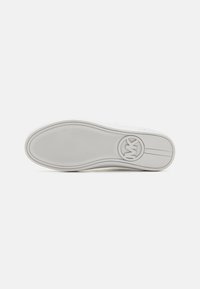 Witte sneakersole met een gestructureerd rubberen oppervlak, gebogenvorm en een cirkelvormig logo met initialen dat prominent in het midden weergegeven is.