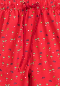 Czerwone kąpielówki z wzorem zielonych szklanek koktajlowych, kawałków limonki oraz napisem "Cześć lato." Posiadają sznurek do regulacji.