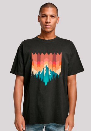 Black t-shirt featuring a graphic design with layered mountains, trees, and a gradient sunset in orange, pink, and teal colors.