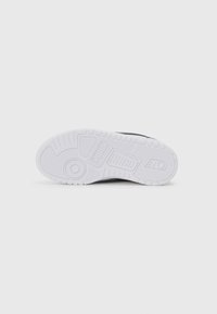 Zwarte sneakers met een gestructureerde rubberen zool, voorzien van een witte buitenzool met een patroon voor grip en logodetails.