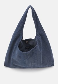 Sac fourre-tout en denim avec une forme unique et une bandoulière simple. Il présente une fermeture par bouton et un tissu doux et texturé dans une teinte bleu foncé.