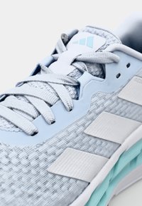 Pantof cu un nuanță deschisă de albastru, de tip sport, cu un material texturat de tricot, vârf întărit, trei dungi albe, accente pastel și o guler căptușit.