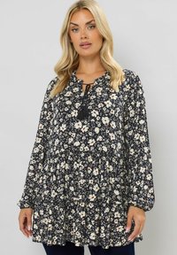 Florale Bluse mit navy Hintergrund und weißen und roten Blumen, entspannter Schnitt, langen Ärmeln und einem Bindedetail am Halsauschnitt.