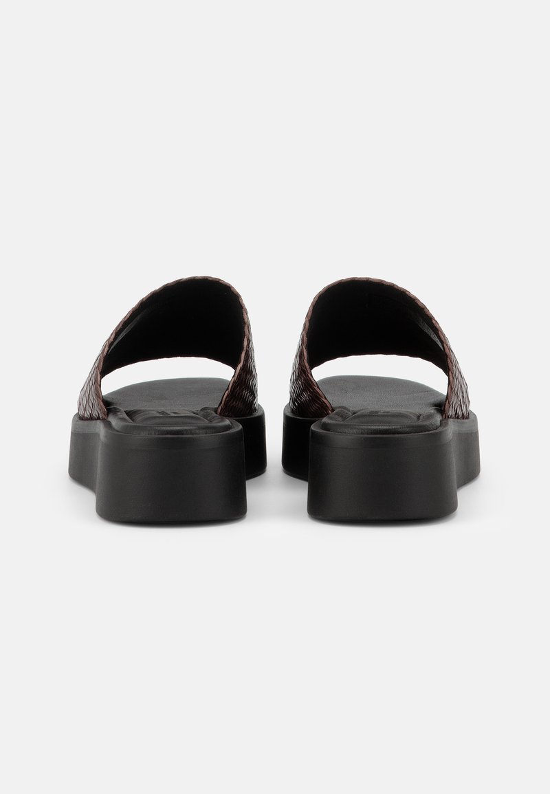 Paar schwarze Plateau-Sandalen mit breiten, strukturierten dunkelbraunen Riemen, von hinten auf weißem Hintergrund gezeigt.