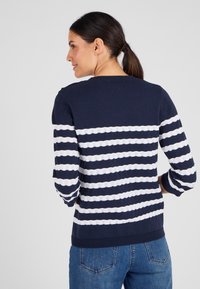 Pullover blu navy con strisce orizzontali bianche, caratterizzato da un design a maglia testurizzata, scollo rotondo e maniche a tre quarti.