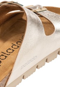 Sandal in argento metallico con finitura testurizzata, design aperto e suola contornata di colore chiaro; presenta una fascia regolabile.
