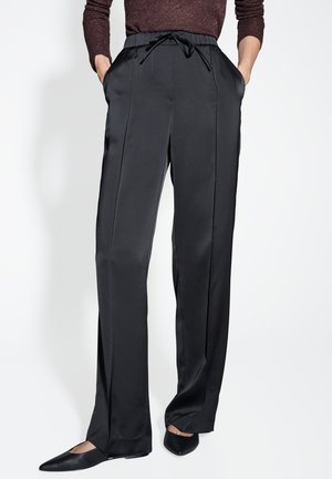 Pantaloni neri a gamba larga realizzati in un tessuto liscio e leggero. Presentano un elastico in vita con coulisse e tasche laterali. Parte anteriore piatta con linee eleganti.