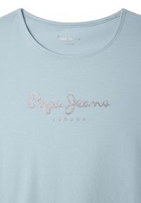 Šviesiai mėlynas medvilninis marškinėliai su apvalia iškirpte, ant krūtinės puikuojasi sidabru blizgantys užrašai "Pepe Jeans London". Lygus paviršius.