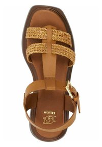 Sandale en cuir marron avec des lanières entrelacées beiges, semelle plate et boucle dorée. Elle possède un lit de pied lisse avec un détail de logo.