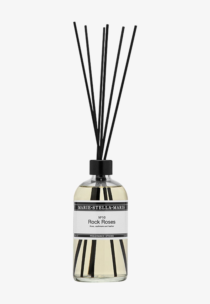 Diffuseur de parfum à tiges avec une bouteille en verre claire, un capuchon noir et six tiges noires. L'étiquette indique "N°10 Rock Roses" avec les notes de fragrance listées.