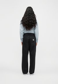 Μαύρο, φαρδύ τζιν με ψηλή μέση και διακριτικές πίσω τσέπες, συνδυασμένο με ανοιχτό γαλάζιο, υφή μακρυμάνικο πουκάμισο.