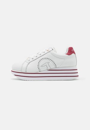 Sneaker piattaforma bianca con suola a righe rosse, logo circolare traforato sul lato, linguetta rossa sul tallone e lacci bianchi.