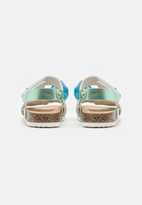Bakvy av sandaler med en kombination av material och ljusblå och gröna detaljer, korkfotbädd och justerbar spänne.