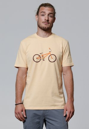 Korte mouwen, ronde hals T-shirt van lichtgele katoen met een grafisch ontwerp van een oranje fiets. Zachte textuur, casual pasvorm.