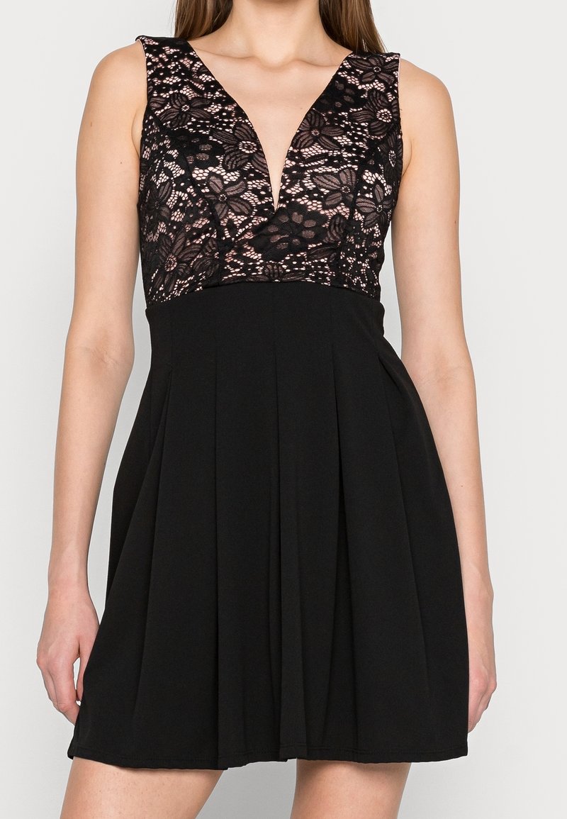 Robe noire sans manches avec corsage en dentelle imprimé floral ajusté et décolleté en V profond, jupe unie évasée se terminant au-dessus du genou.