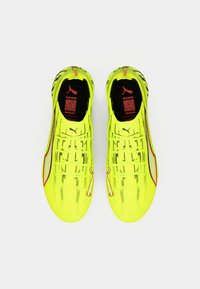 Fluorescerende gule fodboldstøvler med tekstureret overdel, slankt design, røde accenter og Puma-logo. Letvægt og tætsiddende.