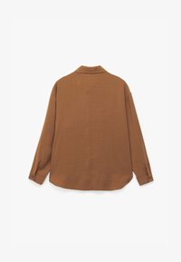 Camisa marrón de corte holgado con cuello, mangas largas y puños con botones, que presenta una textura suave y un diseño de espalda abierta.