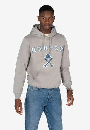 Sudadera gris con el texto "HARPER" en azul, con un gráfico de un casco de obra azul y herramientas cruzadas. Combinada con jeans de un azul claro.