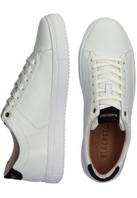 Sneaker bianchi in pelle con lacci piatti, punta arrotondata, suola texture e un accento nero sul tallone che presenta il nome del brand "BLACKSTONE."