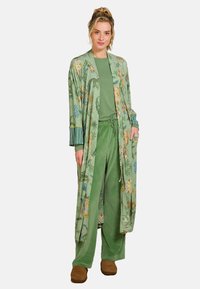 Lange groene bloemenkimono met patronen op de mouwen, gecombineerd met een bijpassende groene top en broek. Zacht materiaal en een ontspannen pasvorm; casual ontwerp.