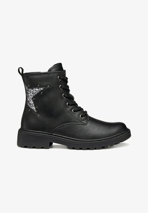 Botines negros hechos de cuero sintético, con un acento de estrella plateada brillante, punta redonda y suela de goma gruesa con agarre.