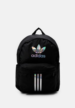 Zwarte Adidas-rugzak met holografisch trefoil-logo en drie verticale strepen op het voorvak, stoffen handvat bovenop.