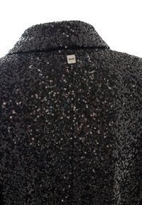 Giacca nera con paillettes e colletto, caratterizzata da una superficie texturizzata. Etichetta in metallo visibile sul retro.