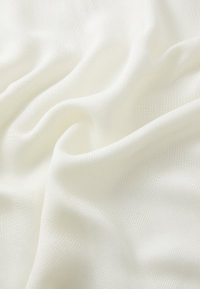Ľahká, textúrovaná tkanina v jemnej bielej farbe, so subtilným, tkaným vzorom, ktorý má jemný pád a fluidnosť.