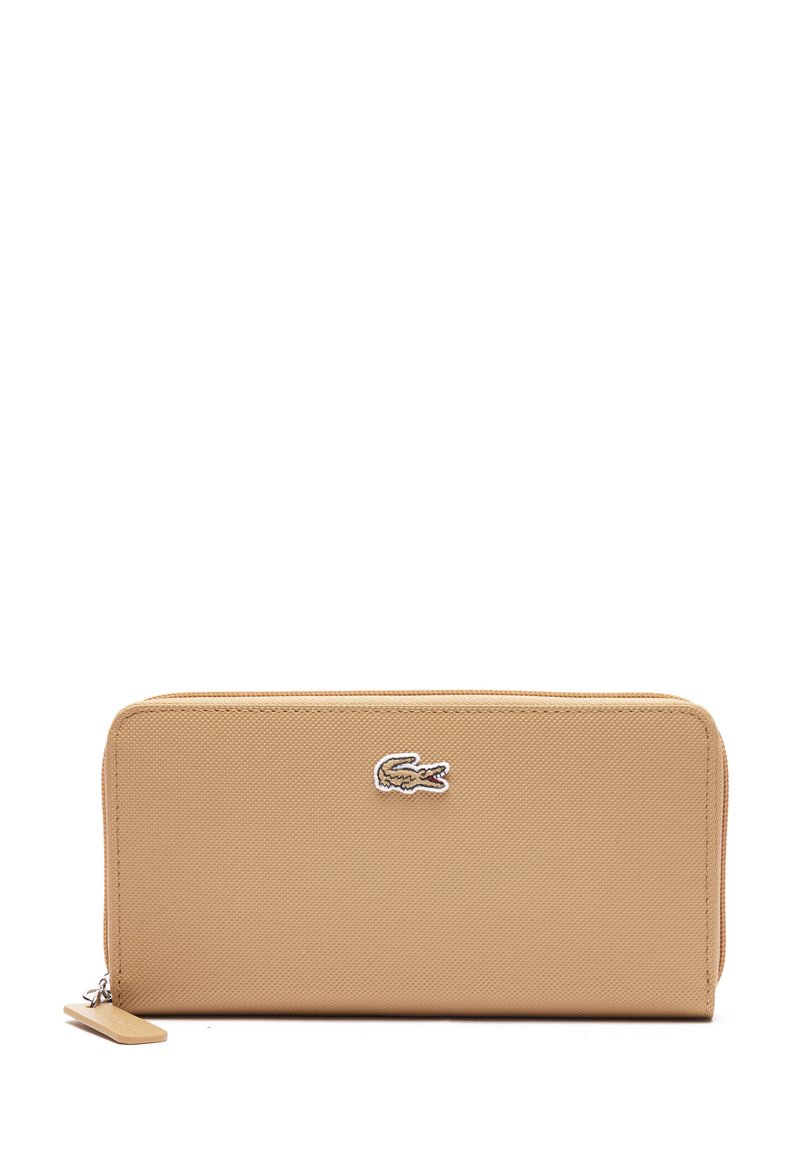 Portafoglio beige in materiale sintetico testurizzato, con chiusura zip e logo Lacoste. Presenta una forma rettangolare con un design liscio e pulito.