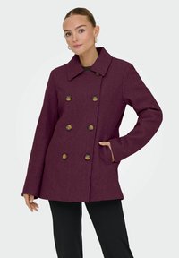 Doppelreiher-Mantel aus tiefem lila Wollmix mit bronzefarbenen Knöpfen, breitem Kragen und seitlichen Taschen für praktische Anwendbarkeit.