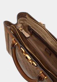 Sac à main synthétique marron avec une texture subtile, quincaillerie dorée et plusieurs compartiments, y compris des poches zippées et ouvertes, avec un revêtement logo.