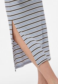 Robe rayée avec des bandes horizontales bleu clair, noires et blanches, dotée d'une fente sur le côté et d'une texture côtelée.