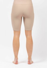 Beige geribbelde actieve shorts met een hoge tailleband, zijzakken en een aansluitend design, eindigend boven de knie. Gladde textuur, geen zichtbare patronen.