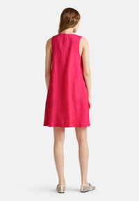 Fuchsia leinen ärmelloses Kleid mit lockerer Passform, ausgestattet mit einem runden Ausschnitt, das bis knapp über das Knie fällt und von flachen, gemusterten Schuhen ergänzt wird.