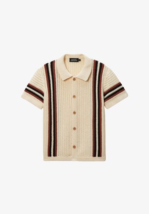 Cardigan court de couleur crème à manches courtes avec un tricot texturé, présentant des rayures verticales marron et noires et des boutons marron sur le devant.