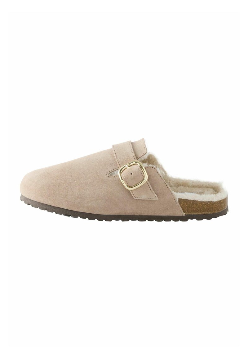 Beige suede klomp met een band en gouden gesp, gevoerd met zachte nepbont, voorzien van een bruine rubberen zool en een ronde tekening.