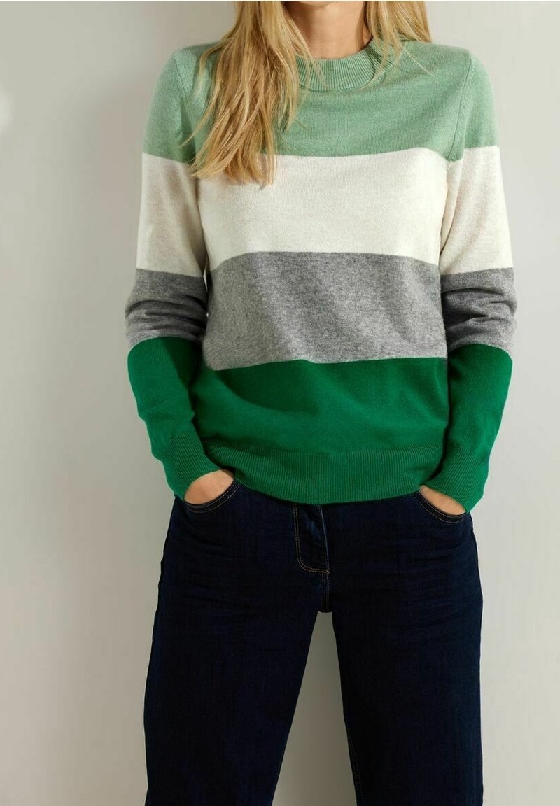 Suéter de punto con rayas horizontales en verde claro, blanco, gris y verde oscuro. Escote redondo y dobladillo acanalado. Combinado con jeans oscuros.