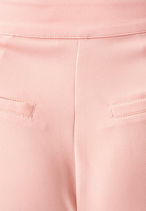 Vaaleanpunaiset housut, joissa on sileä pinta, kahdella takataskulla ja siistillä ompeluksella vyötärönauhassa ja saumoissa.